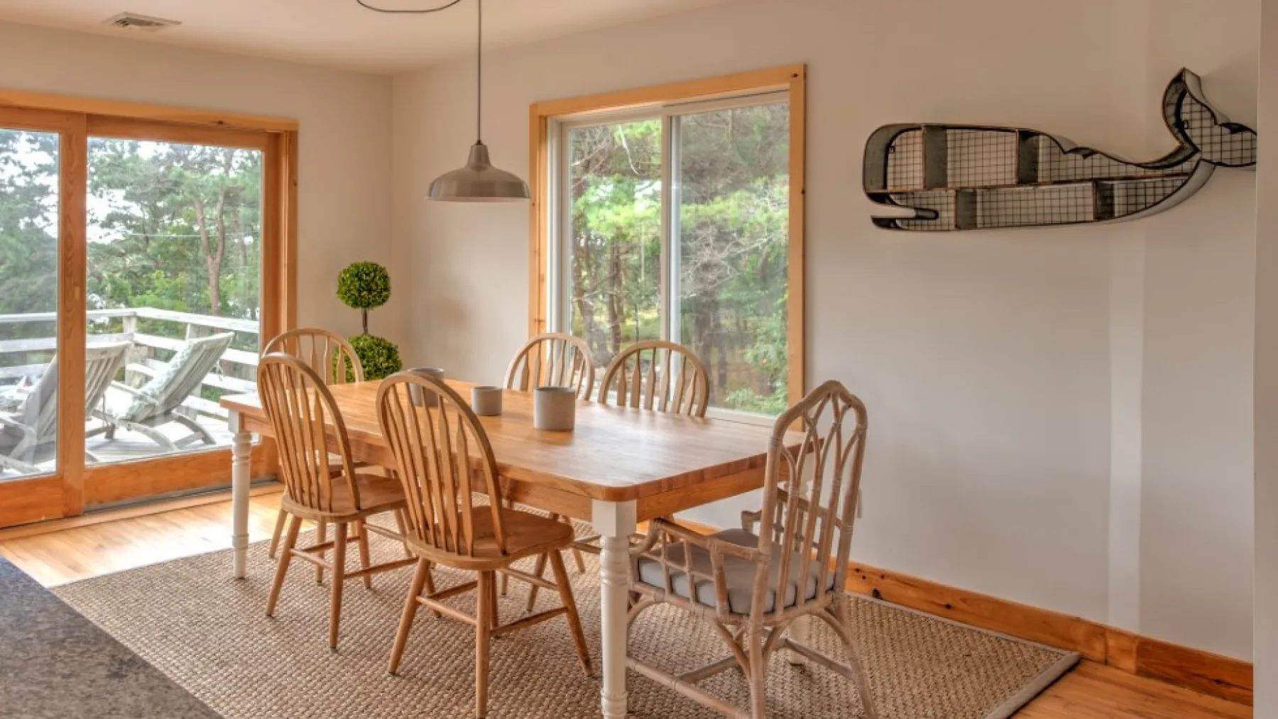 Un comedor luminoso con una mesa de madera y sillas junto a grandes ventanas.