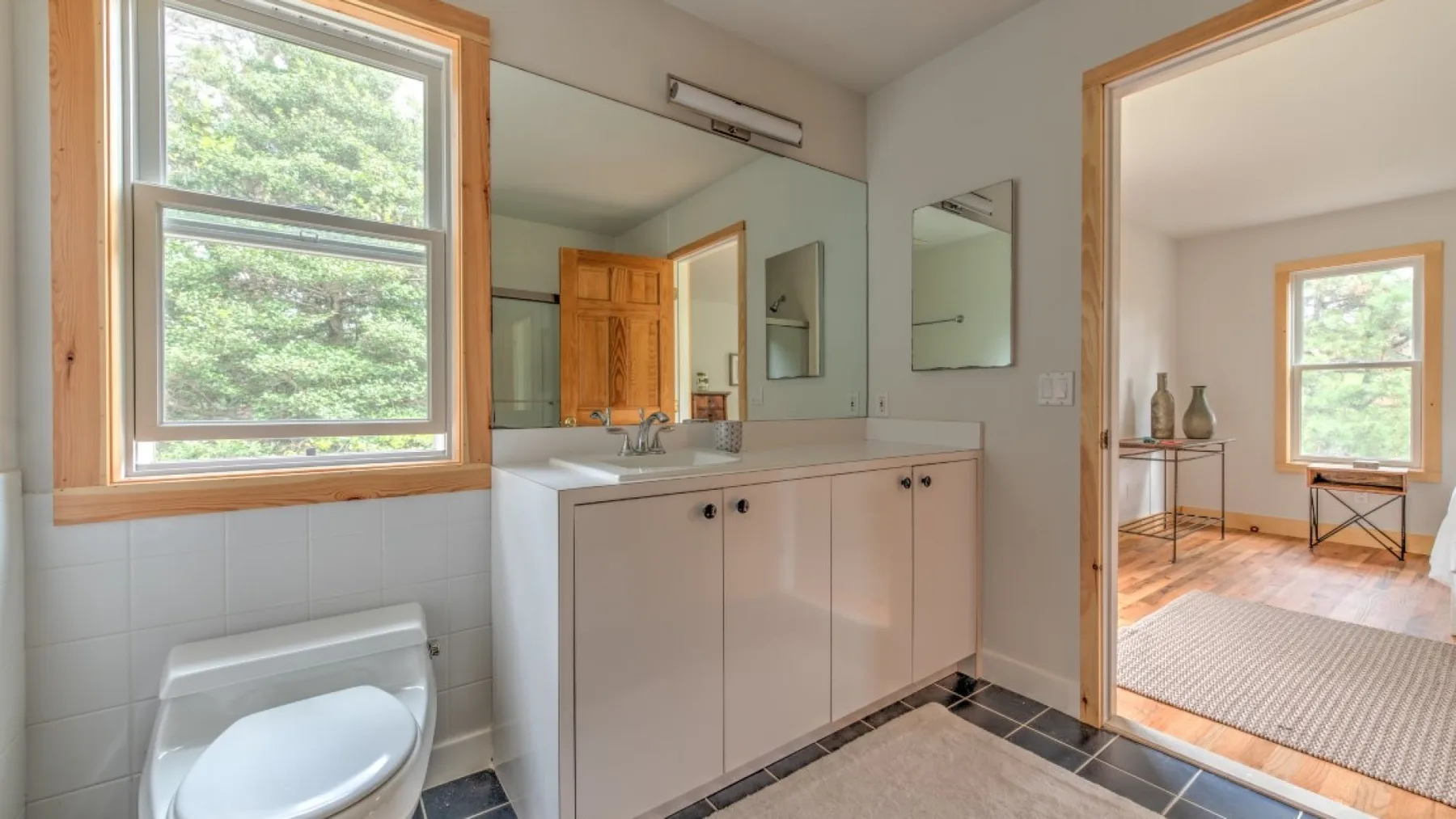 Un baño con lavabo y mueble junto a una ventana grande.