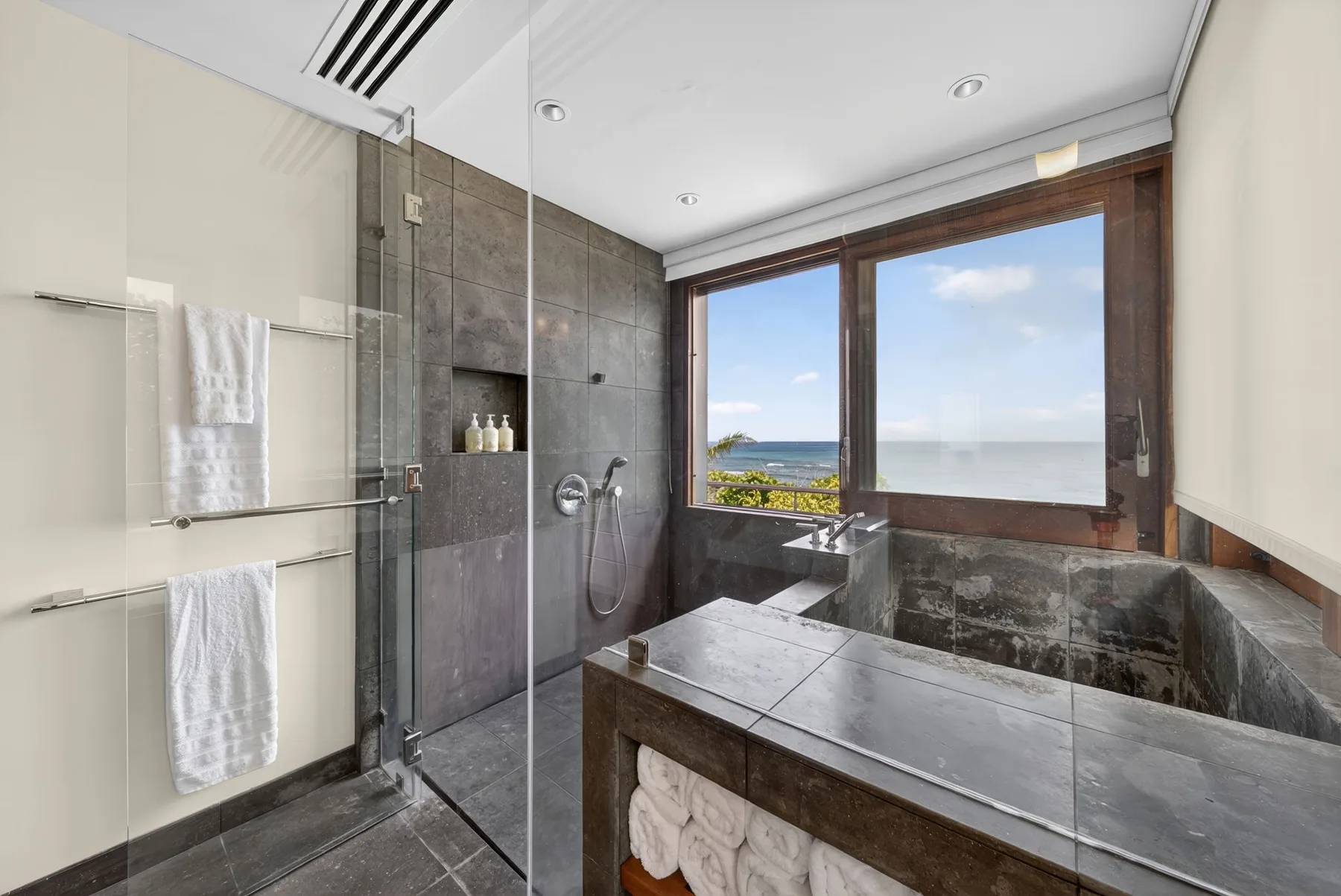 Un baño moderno con una bañera amplia y una ventana con vistas al mar.