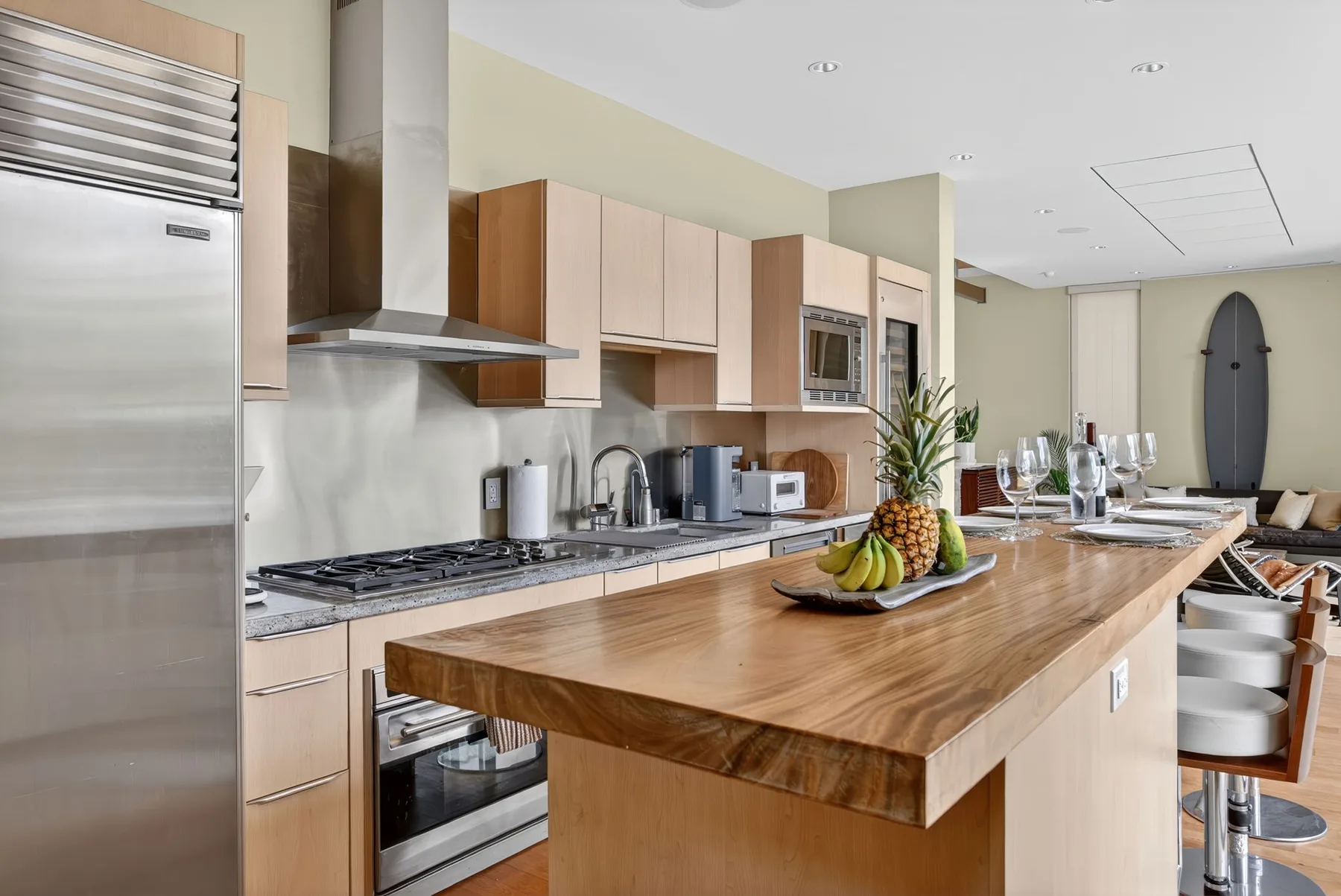 Una cocina luminosa con una gran isla de madera y electrodomésticos de acero inoxidable.