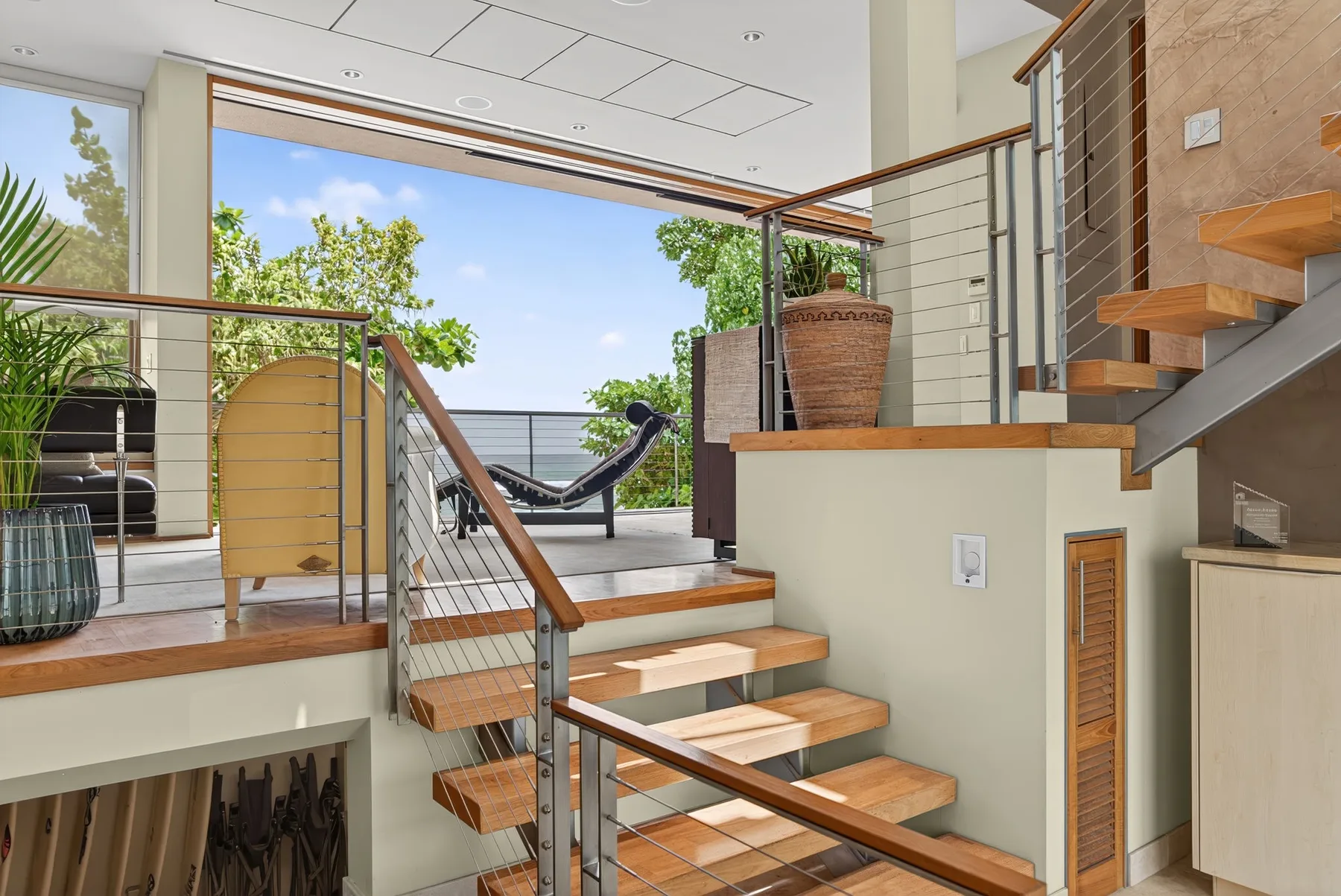Una escalera interior abierta conduce a una terraza soleada con una hamaca y plantas en macetas.