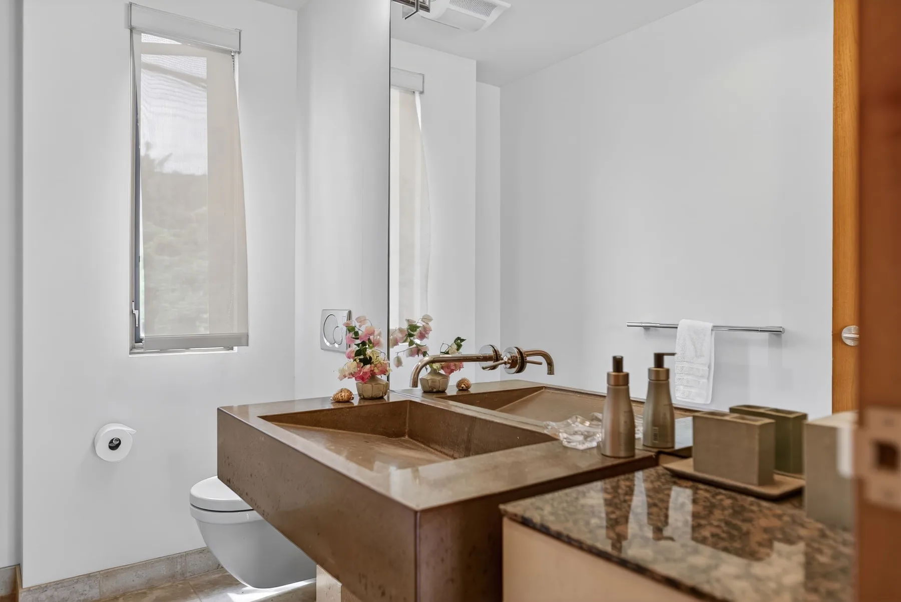 Un baño luminoso con un amplio lavabo de piedra y una ventana.