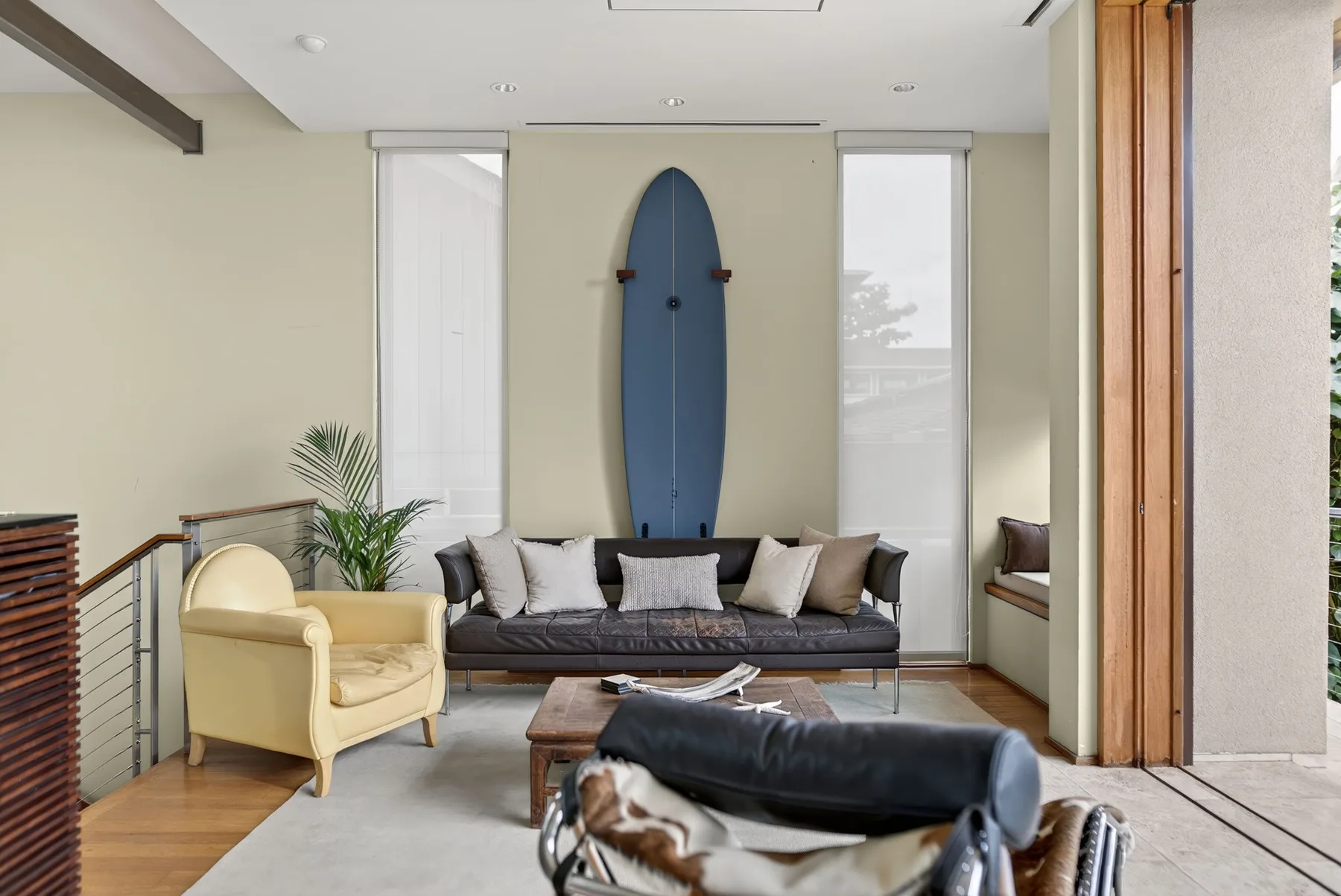 Una sala luminosa tiene asientos alrededor de una mesa baja y una tabla de surf en la pared.