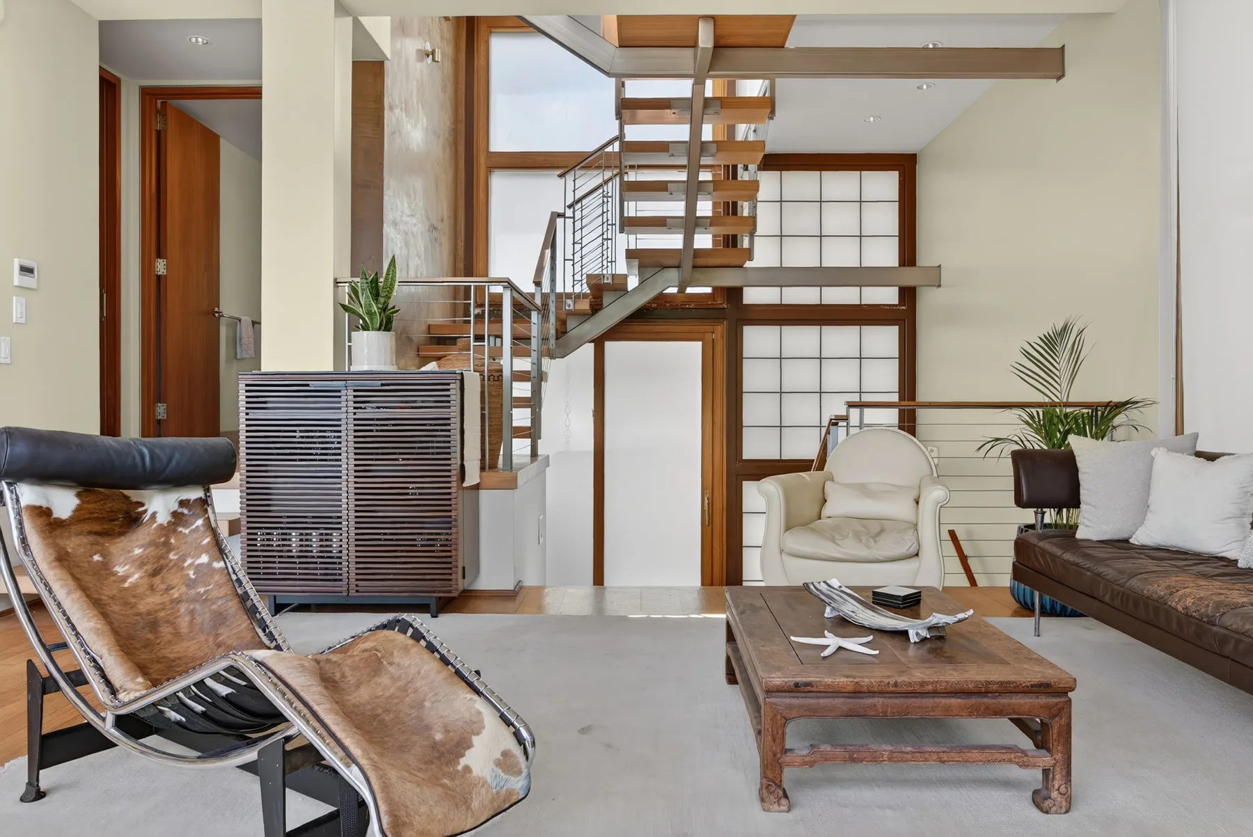 Una sala de estar moderna con una mesa de centro de madera y una escalera abierta.