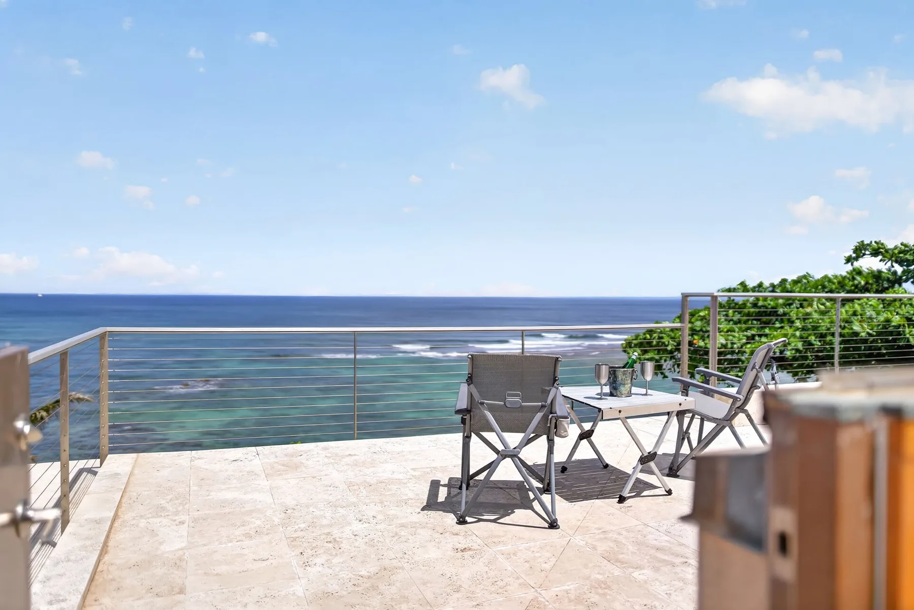 Una terraza frente al mar con asientos al aire libre y una barandilla metálica.