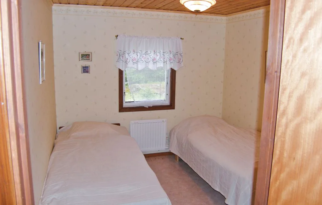 A bedroom with two beds and a window with a lace curtain.