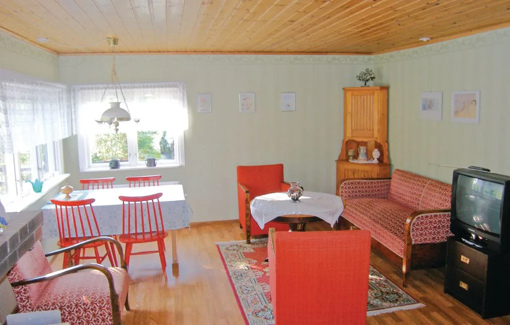 Una sala de estar con asientos estampados, una mesa de comedor y un televisor.