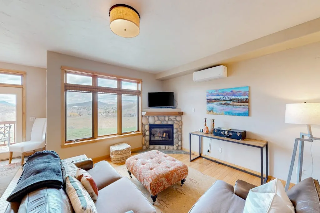 A living room with a fireplace, large windows, and seating.