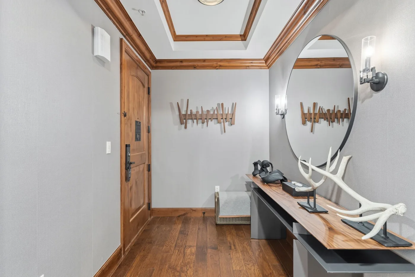 Un recibidor con una puerta de madera, una consola y ganchos decorativos en la pared.