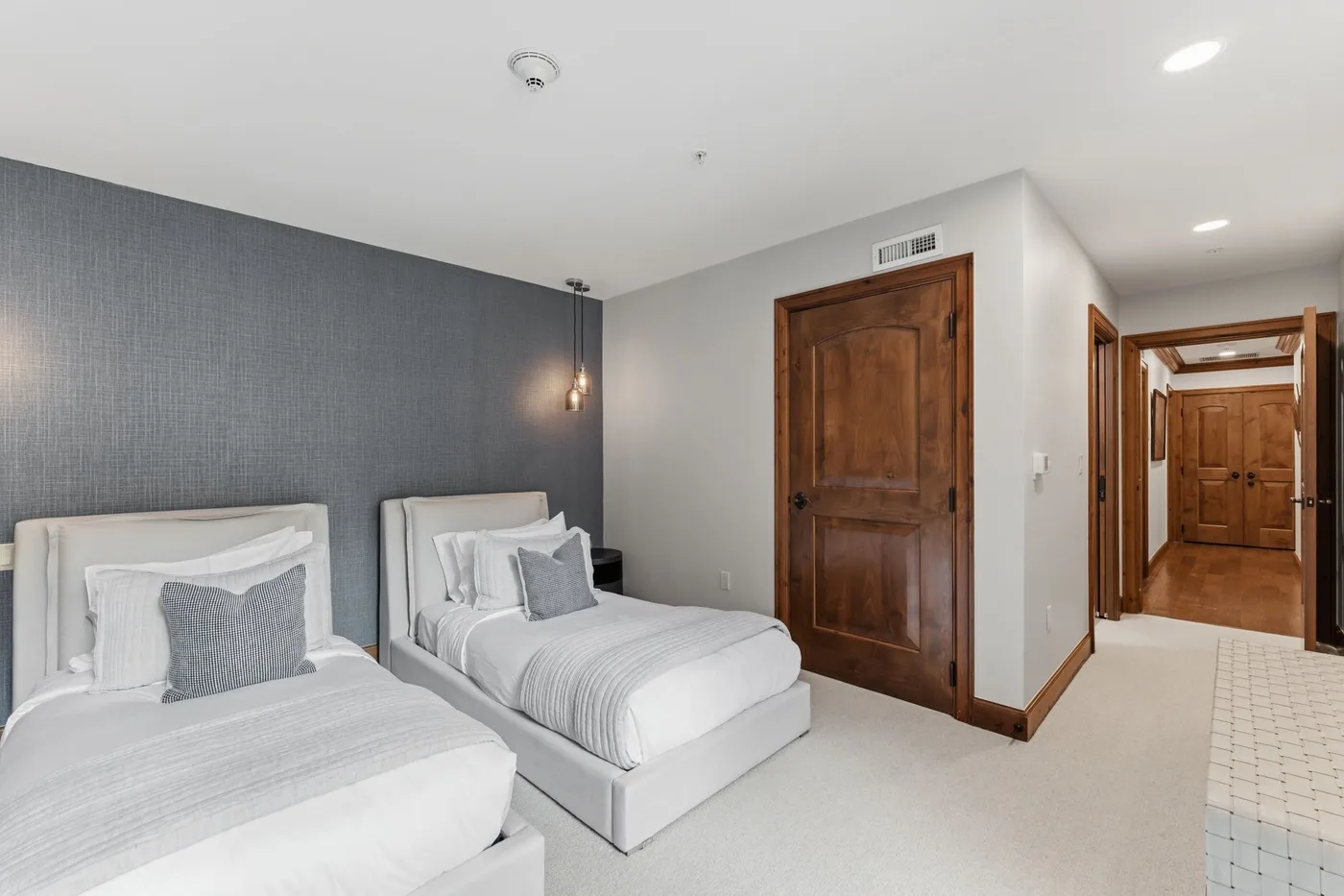 Un dormitorio con dos camas junto a una pared oscura texturizada y una puerta de madera.