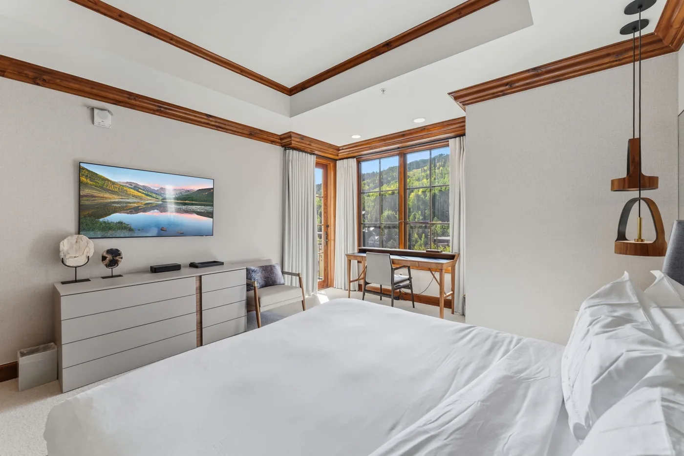 Un dormitorio luminoso con una cama grande y un escritorio junto a la ventana.
