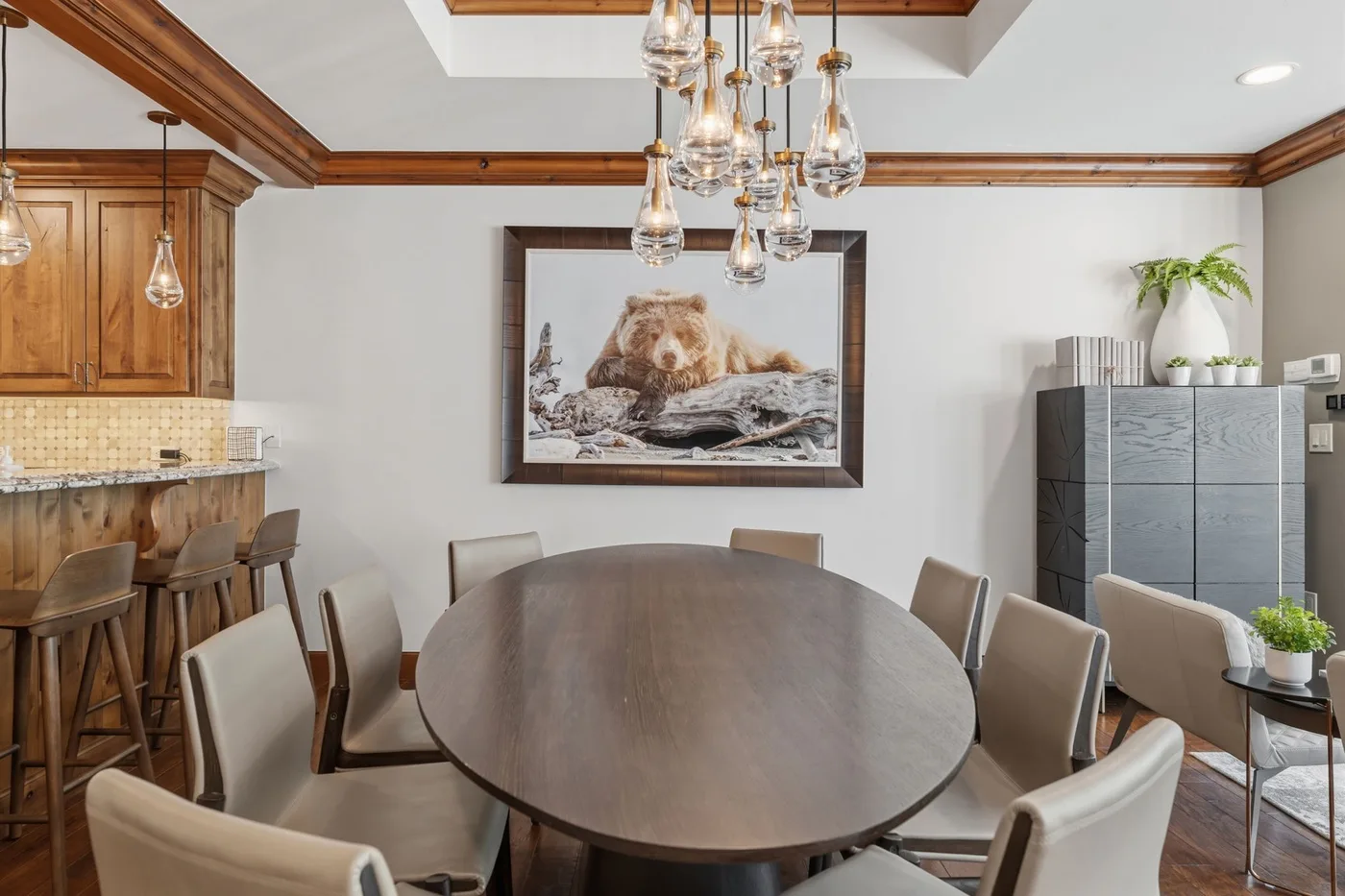 Comedor con una gran mesa ovalada bajo lámparas colgantes de vidrio.