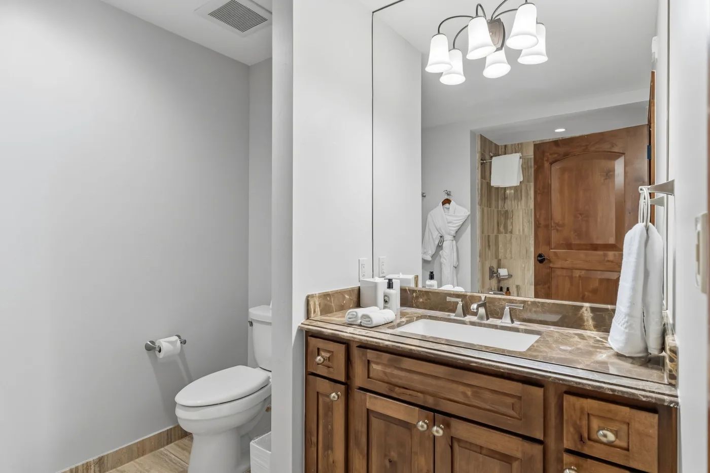Un baño con mueble de madera, espejo e inodoro.