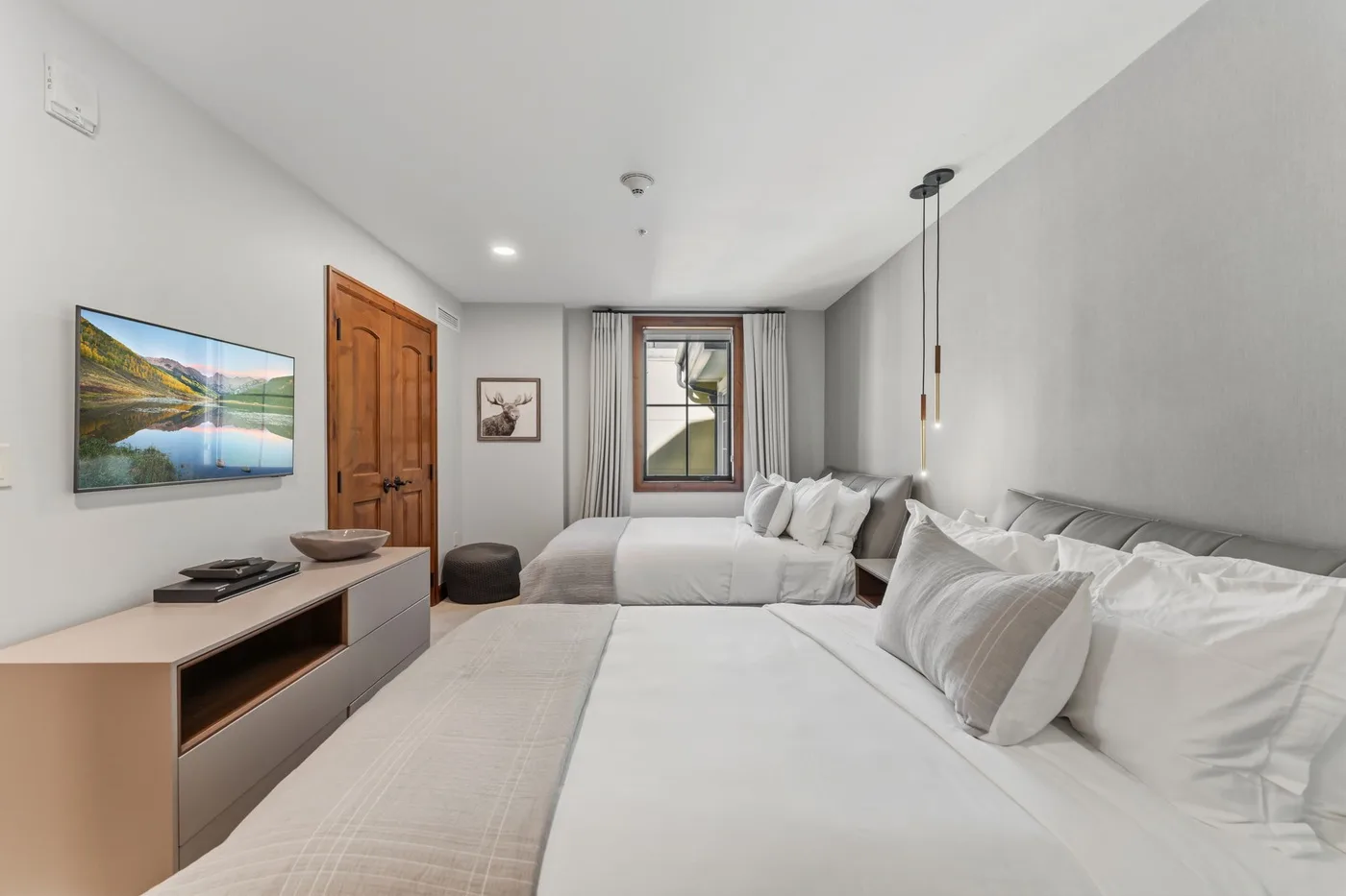 Un dormitorio luminoso con dos camas, una ventana y un televisor.