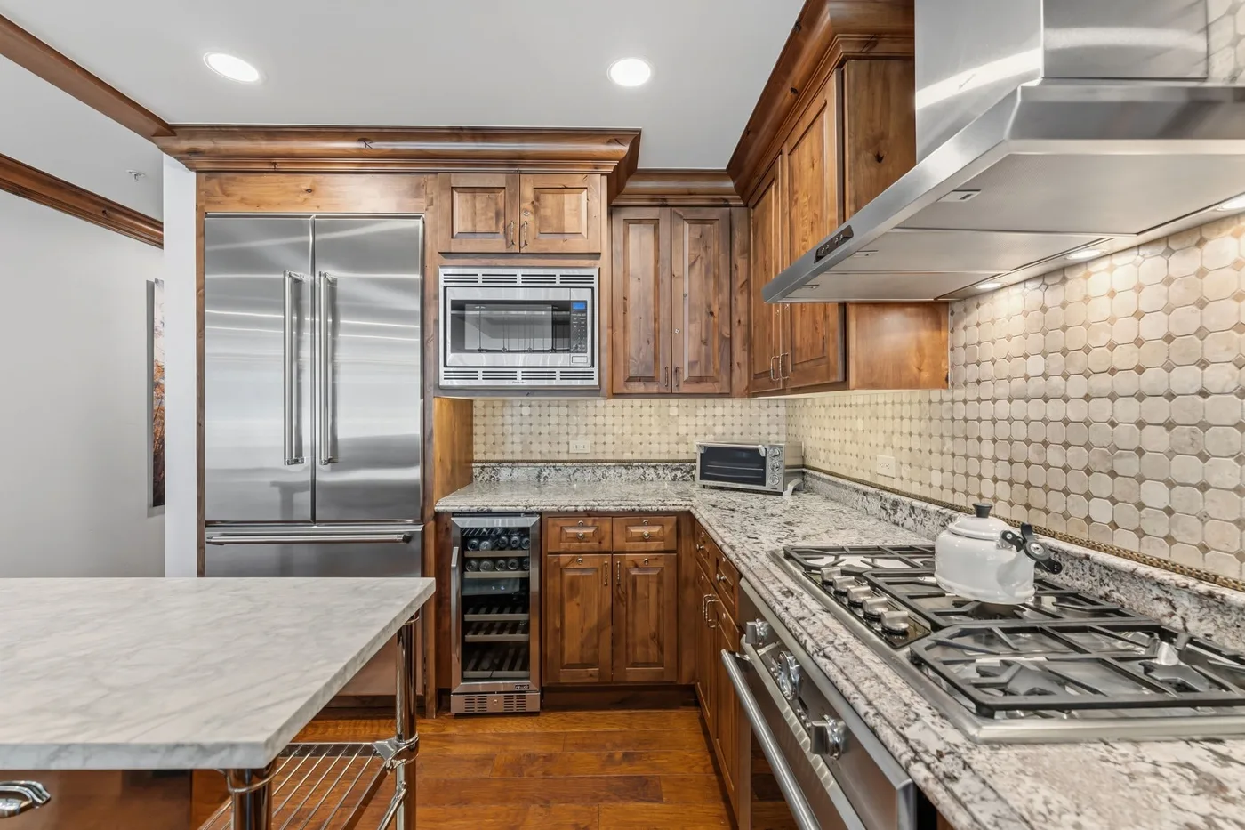 Una cocina con gabinetes de madera, electrodomésticos de acero inoxidable y una amplia estufa.