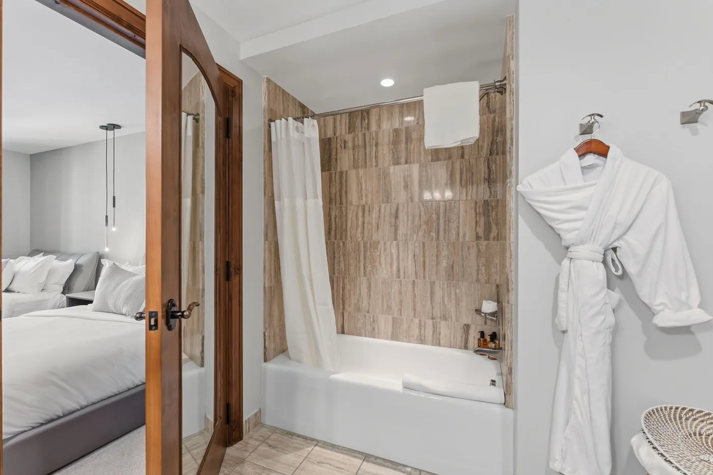 Un baño con bañera, cortina de ducha y una bata blanca colgada.