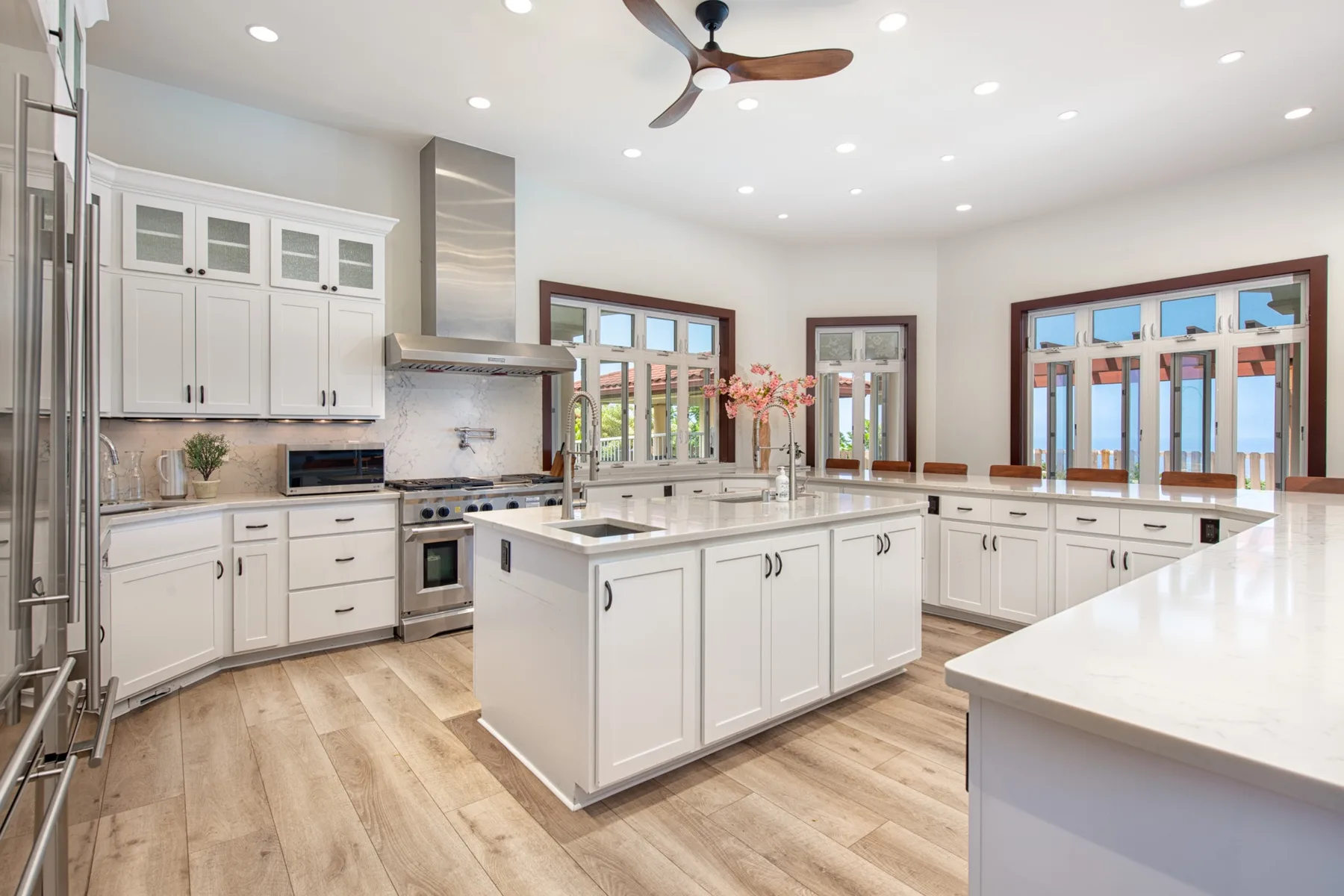 Una cocina luminosa con gabinetes blancos, una isla grande y ventanas amplias.
