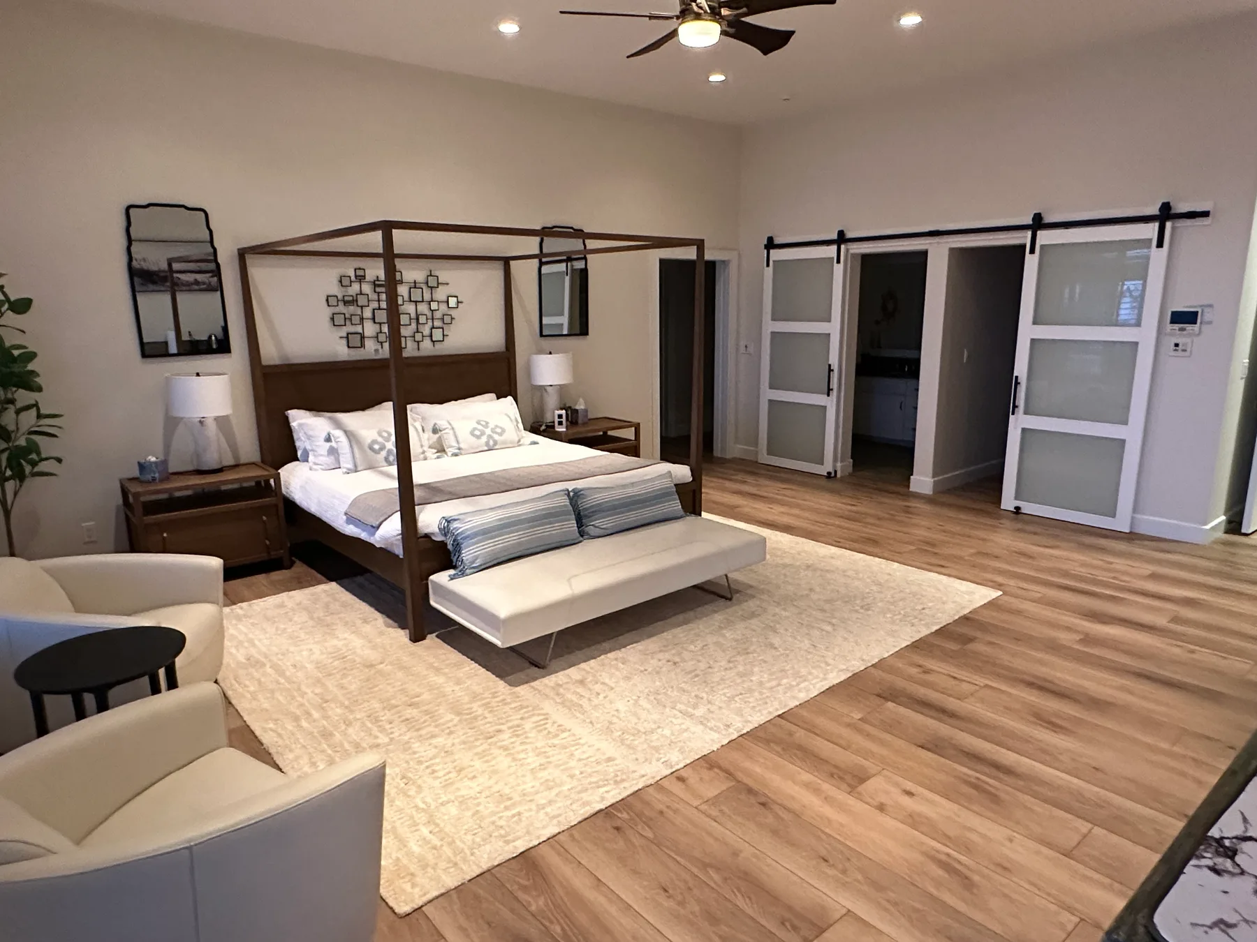 Un dormitorio con una cama con dosel, un banco y puertas corredizas.