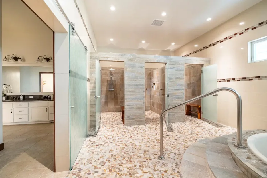 Un baño amplio con zonas de ducha revestidas de azulejos y una mampara de vidrio.
