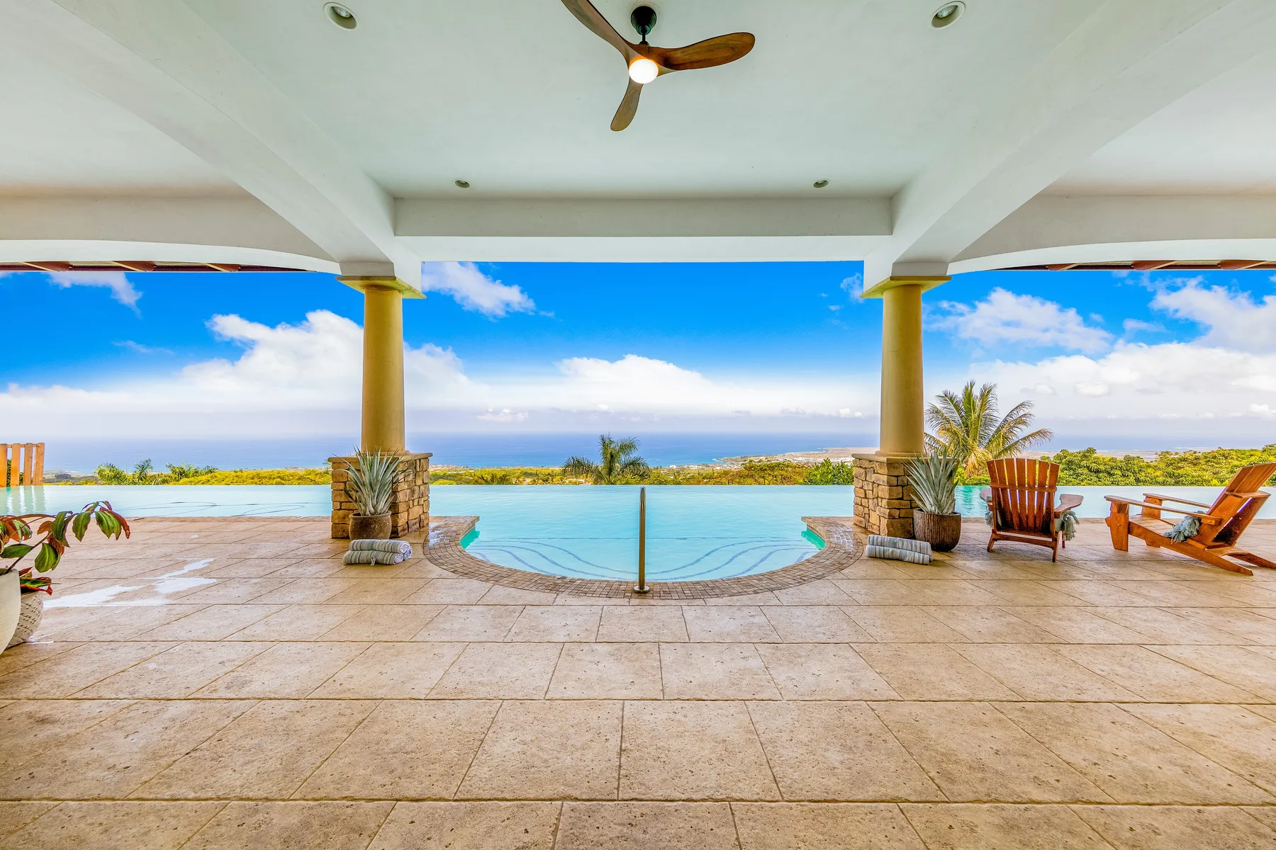 Un patio cubierto da a una piscina con vistas al océano.