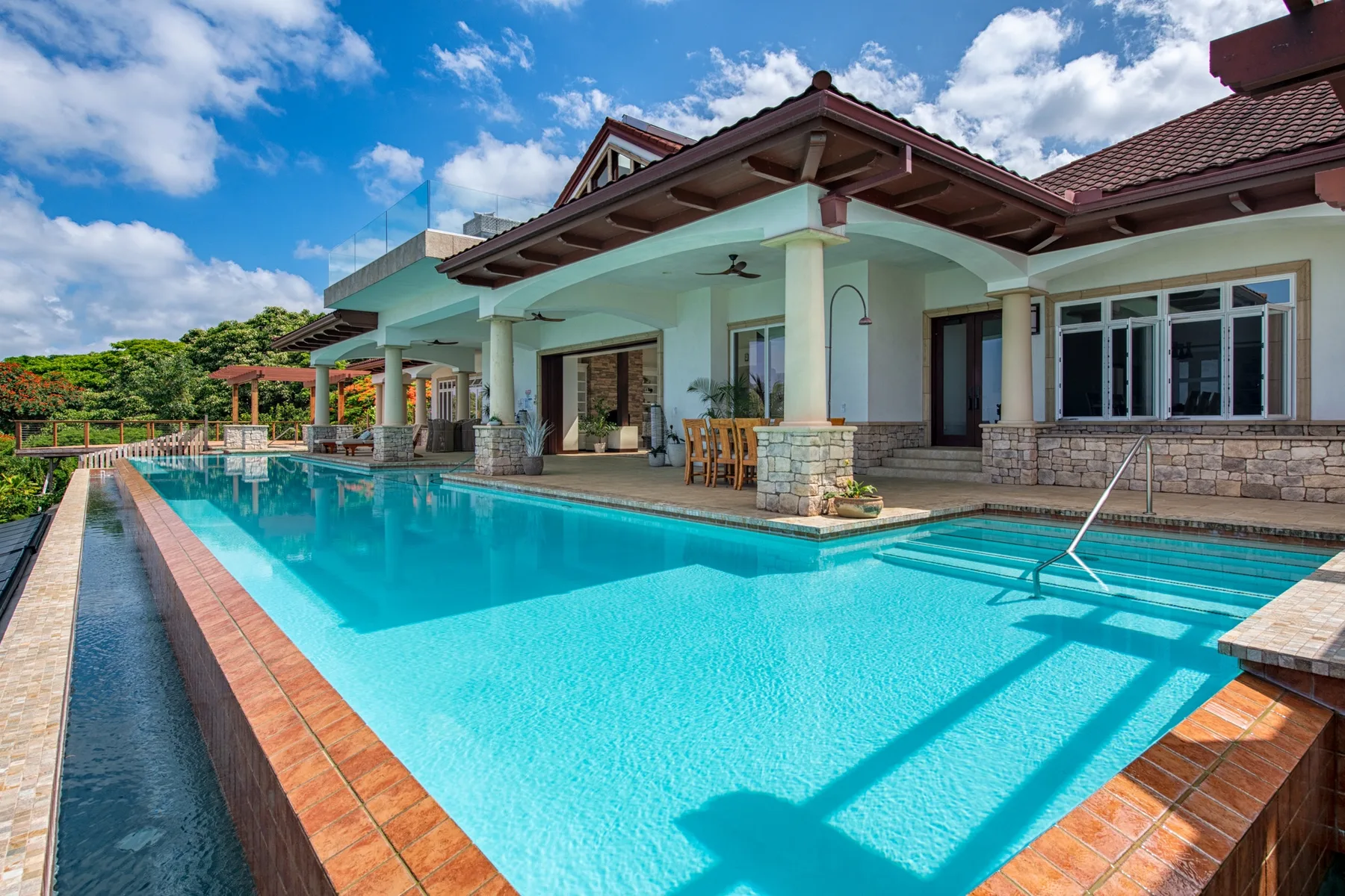 Una piscina junto a un patio cubierto y una casa grande.
