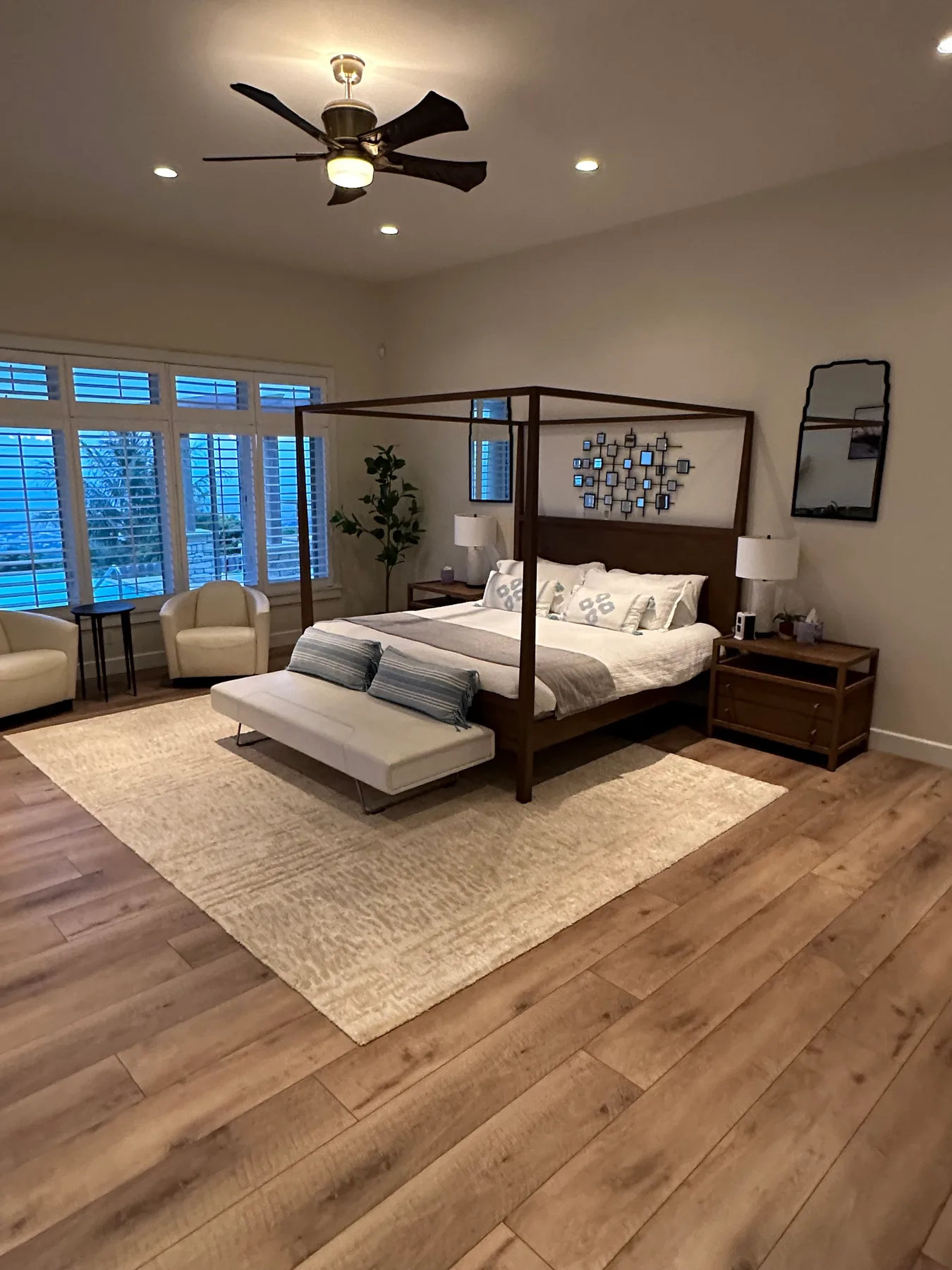 Un dormitorio con una cama con dosel, asientos y grandes ventanas.