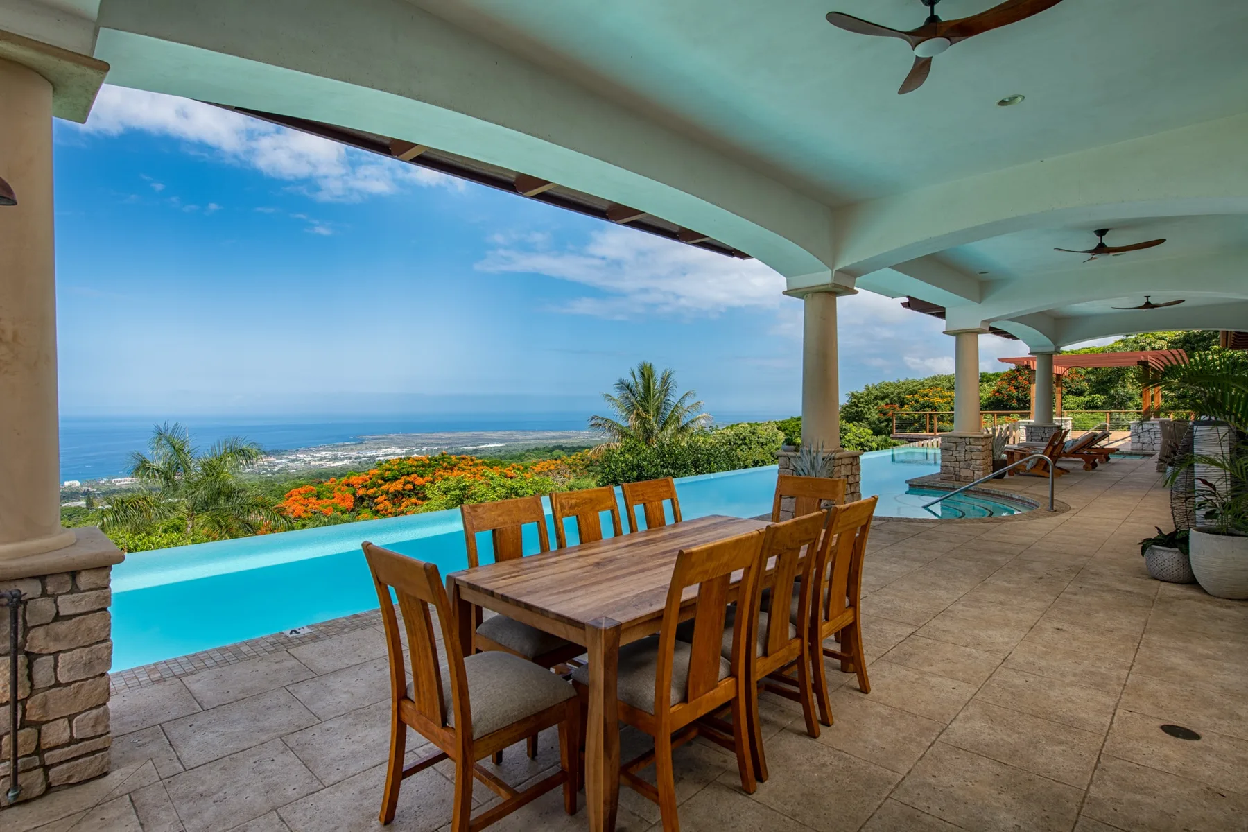 Un comedor exterior cubierto da a una piscina y al océano.
