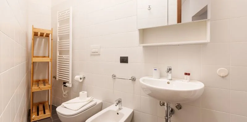 A tiled bathroom with a sink, toilet, and bidet.