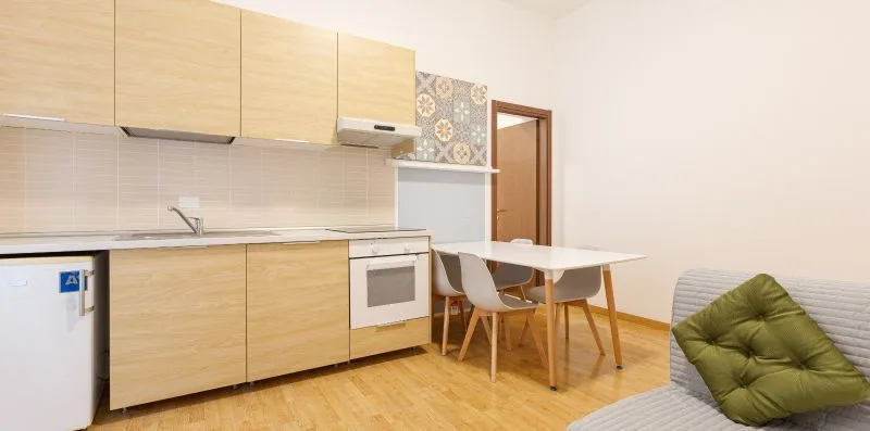 A compact kitchen and dining area with light wood cabinets and a table.