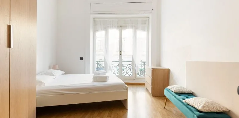 A bright bedroom with a bed and glass doors opening onto a balcony.