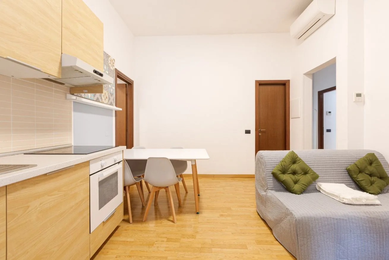 A bright open-plan kitchen and living area with a dining table and seating.