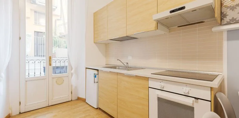 A bright kitchen with light wood cabinets, a countertop, and an oven.