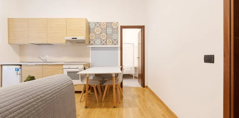 A compact kitchen and dining area with light wood cabinets and a table.