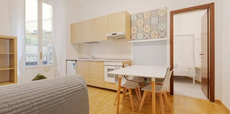 A bright kitchenette with a dining table beside a window and an open doorway.