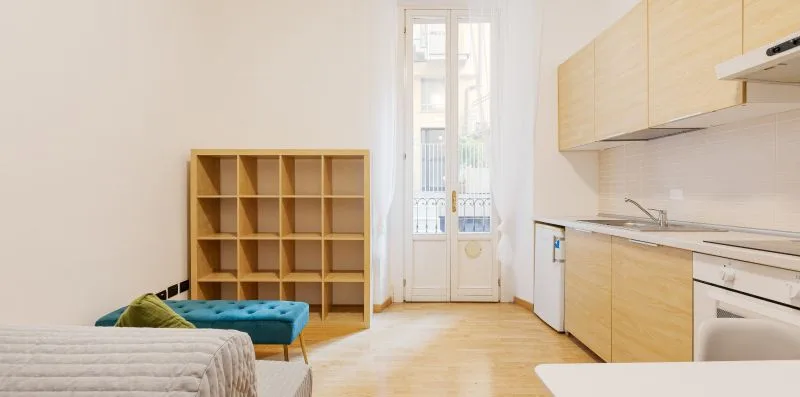 A bright kitchen and dining area with light wood cabinets and a tall window.