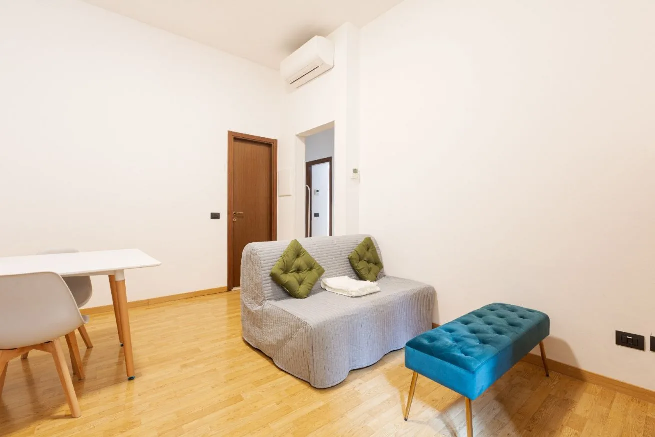 A bright living room with seating, a low table, and a dining table.