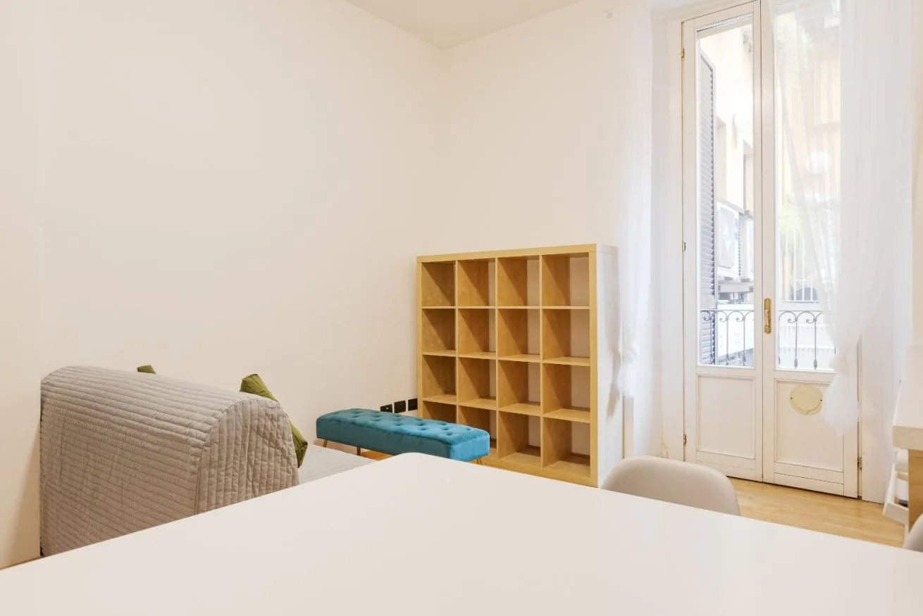 A bright living room with a wooden cubby shelf and tall glazed doors.