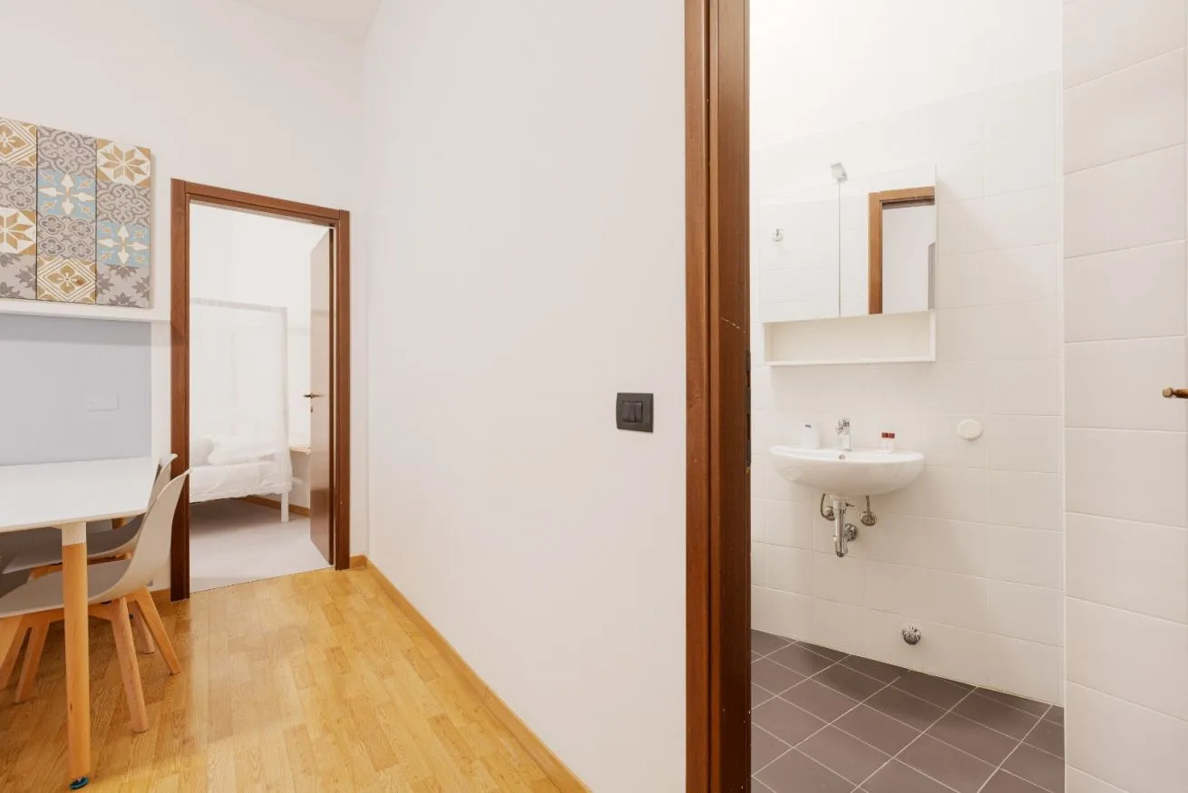 A bright room with a dining table beside an open bathroom.