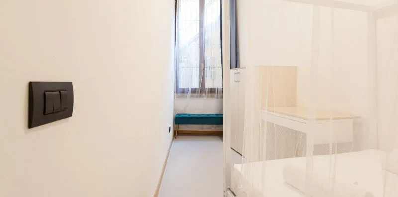 A bright bedroom with a bed beside a tall window.