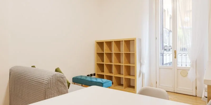A bright room with a low storage shelf and a large window.