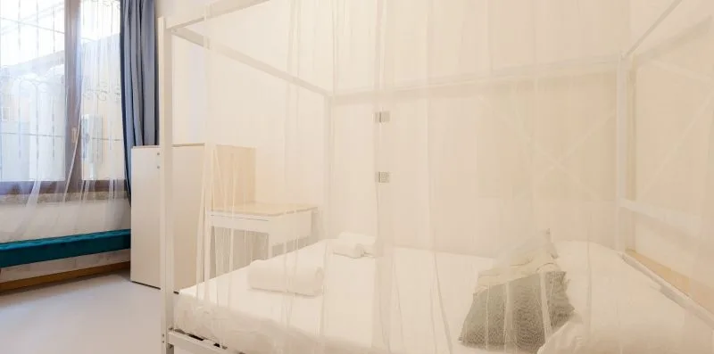 A bright bedroom with a white canopy bed and a window.