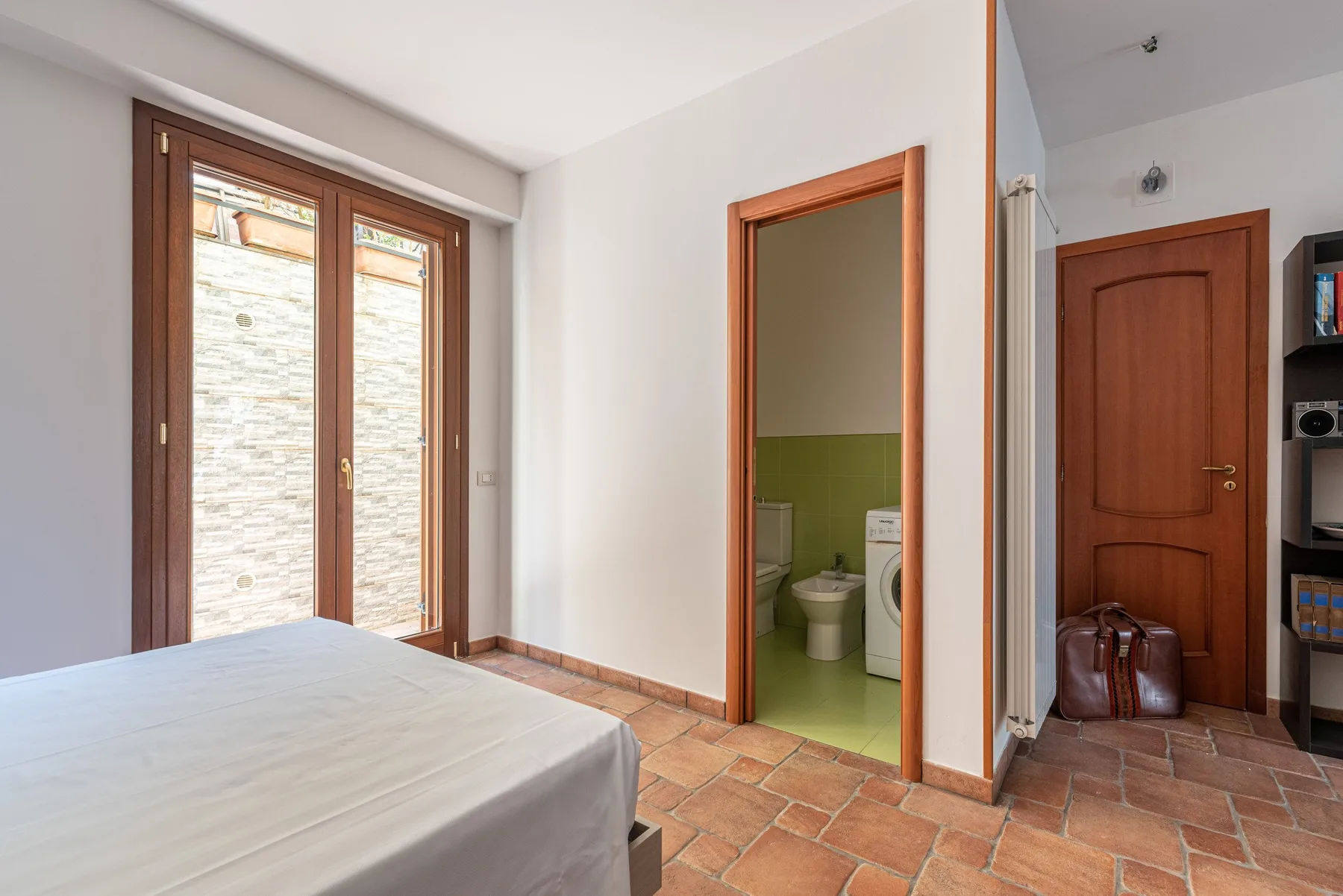 Un dormitorio con una cama junto a la entrada de un baño.