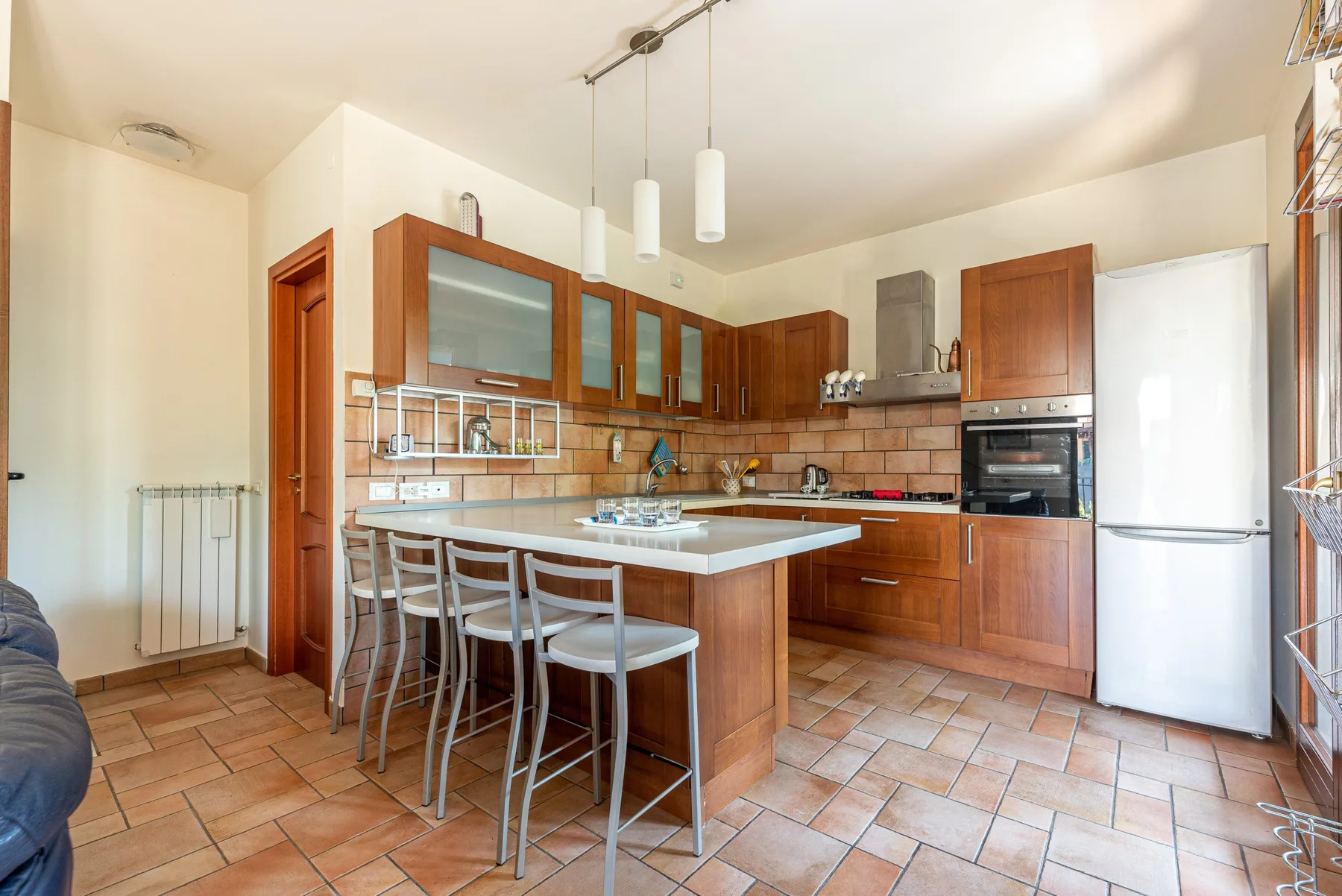 Una cocina amplia con gabinetes de madera, una barra central y un refrigerador.