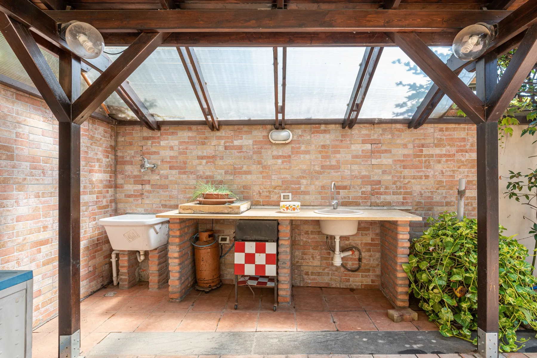 Una zona de cocina exterior cubierta con encimeras de ladrillo y un fregadero.