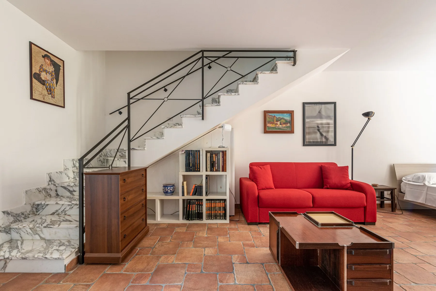 Sala de estar con asientos rojos, una mesa de centro y una escalera.