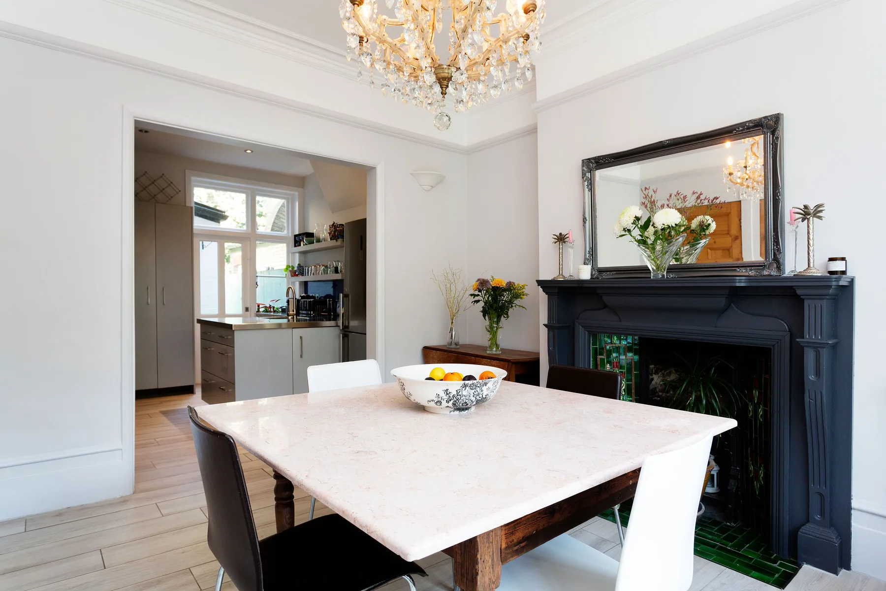 A bright dining room with a white table and a dark fireplace.