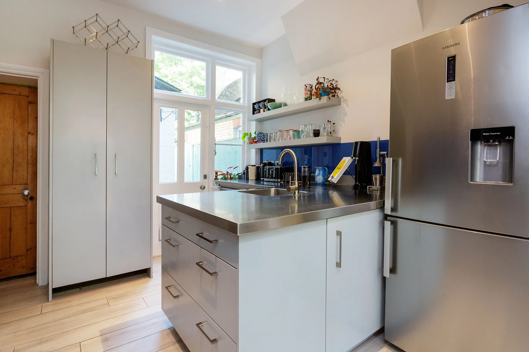 A bright kitchen with a central island and stainless-steel refrigerator.