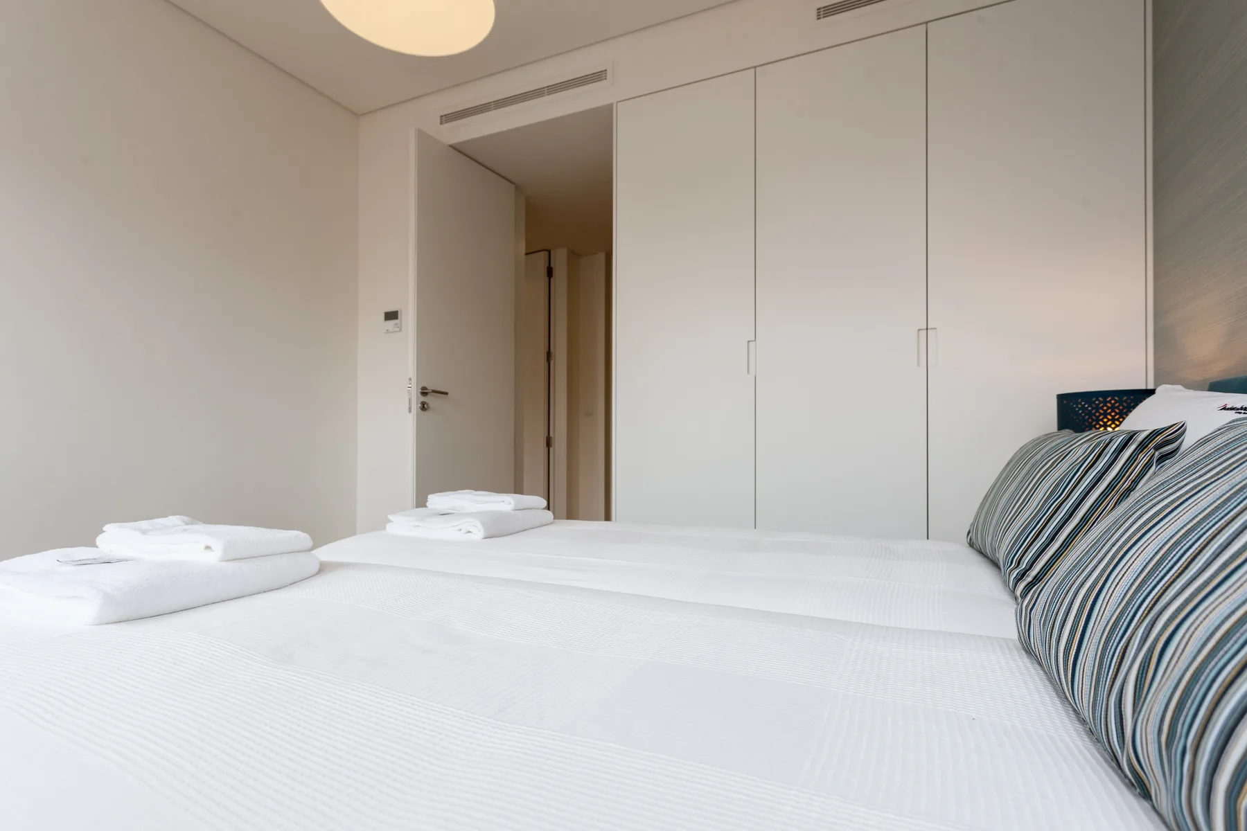 Un dormitorio con una cama bien hecha y almohadas a rayas.