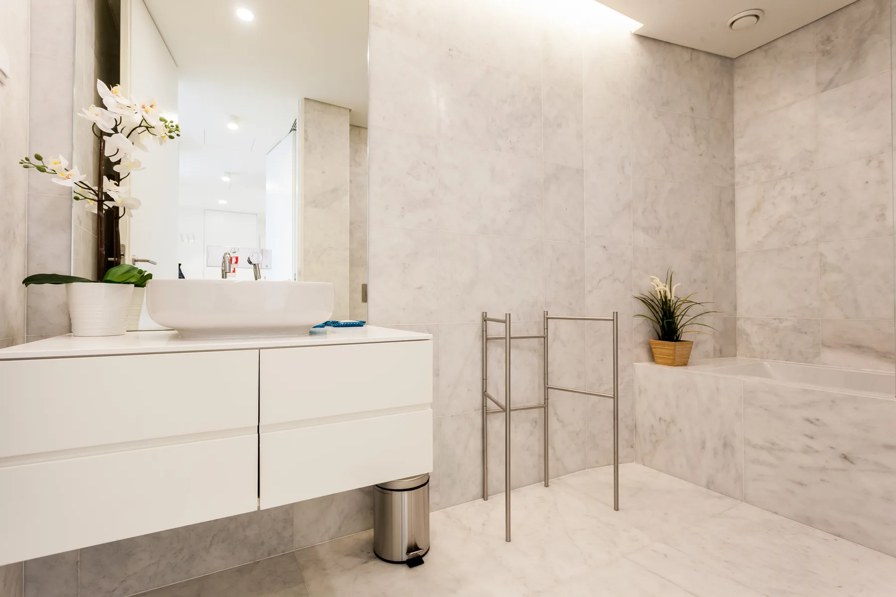 Un baño luminoso con un tocador blanco y una bañera empotrada.
