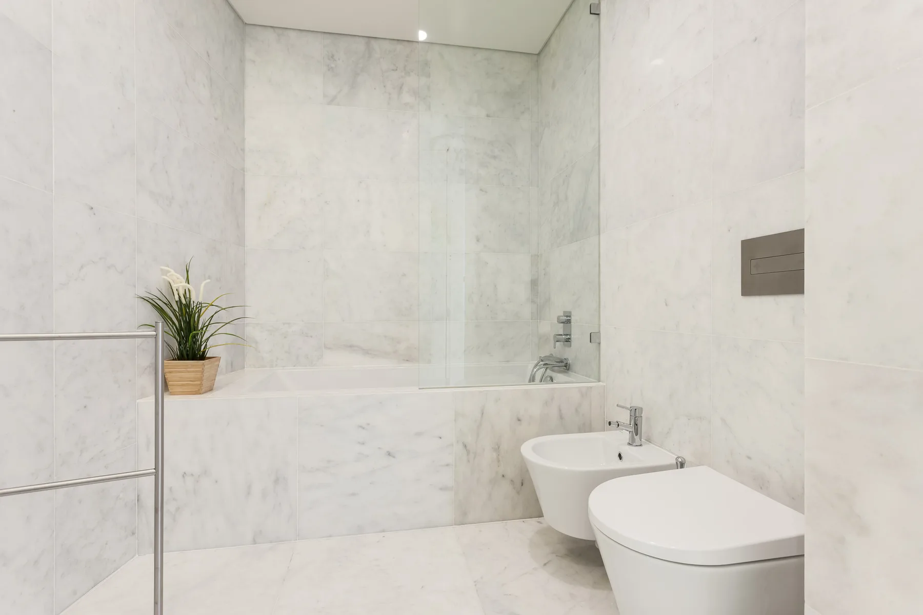 Un baño luminoso con bañera, inodoro y una pequeña planta en maceta.